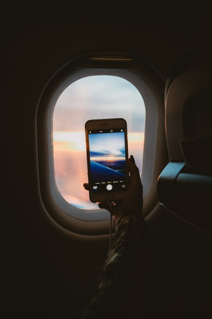 person holding smartphone inside airplane