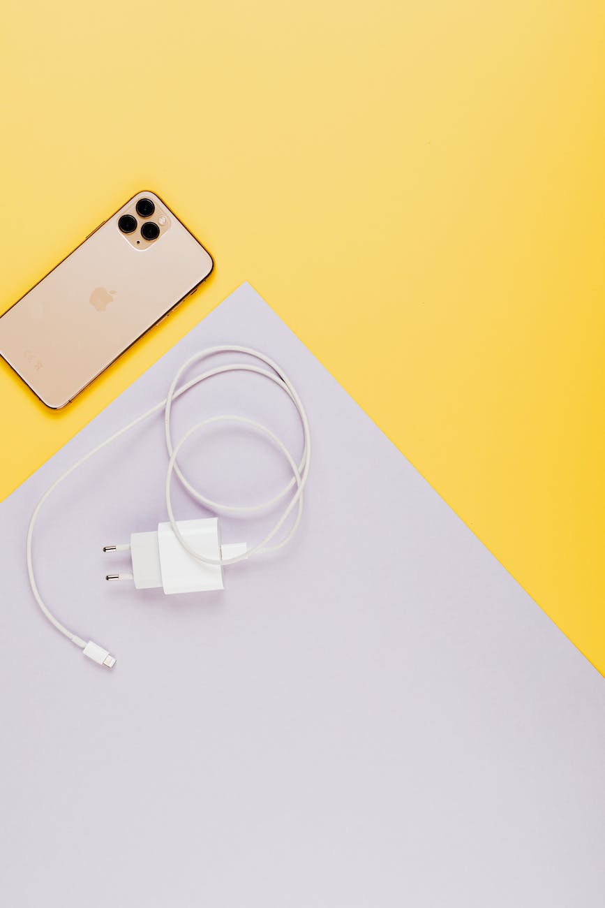 close up shot of a mobile phone and a charger on a yellow surface